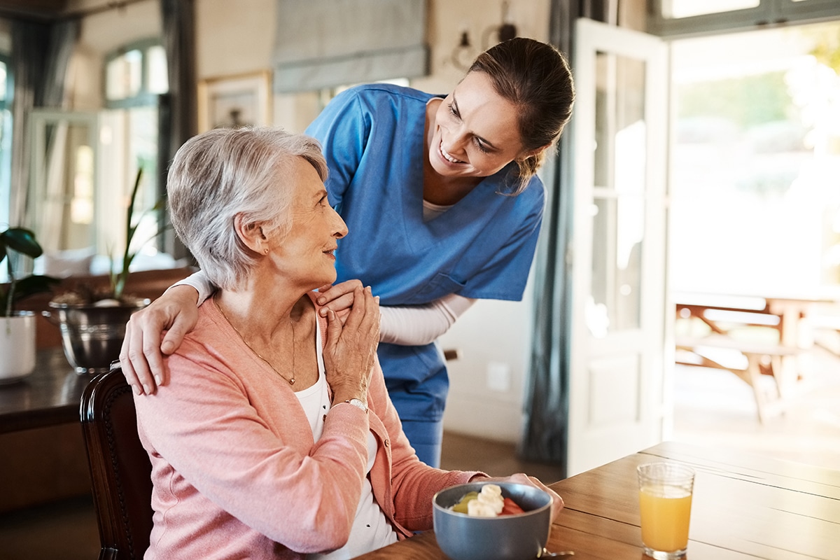older woman with nurse with breakfast at her home and at the table