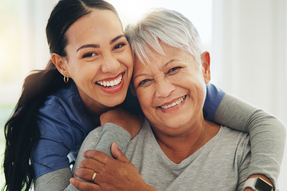 Happy nurse hugging senior patient